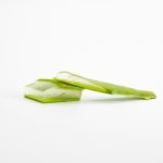 Fresh celery stalks with leaves on a white surface
