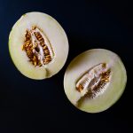 Honeydew melon cut in half showing green flesh and seeds