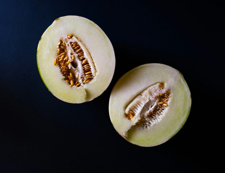 Honeydew melon cut in half showing green flesh and seeds
